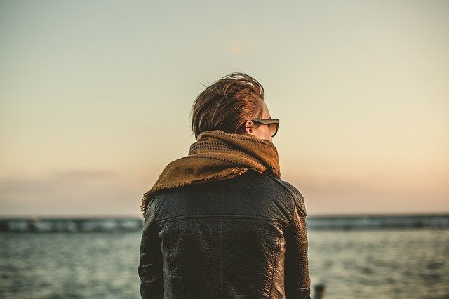 A person staring at the ocean and thinking about moving from the US to Europe.