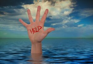 A drowning man with his hand above the water, and word help written on his palm.