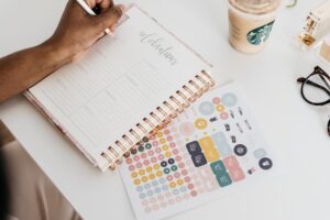 A woman writing plans for saving space when packing office supplies in her notebook.