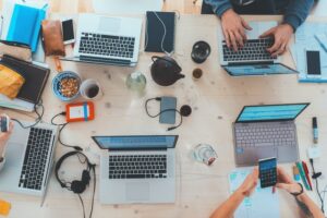 A desk with a lot of laptops and other technology items.