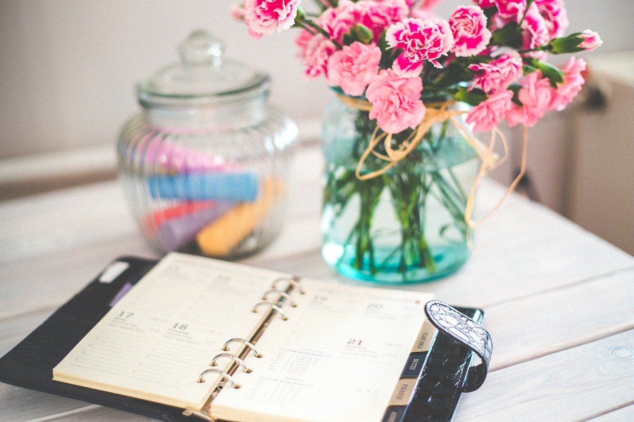 Flowers in a vase and a planner to make notes when organizng a stress-free move.