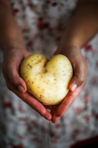 a heart shaped potato held between two hands.