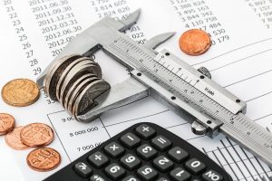 A calculator and a pile of coins squeezed together symbolizing the amount of money one needs for purchasing a property in accordance with Las Vegas real estate investment predictions