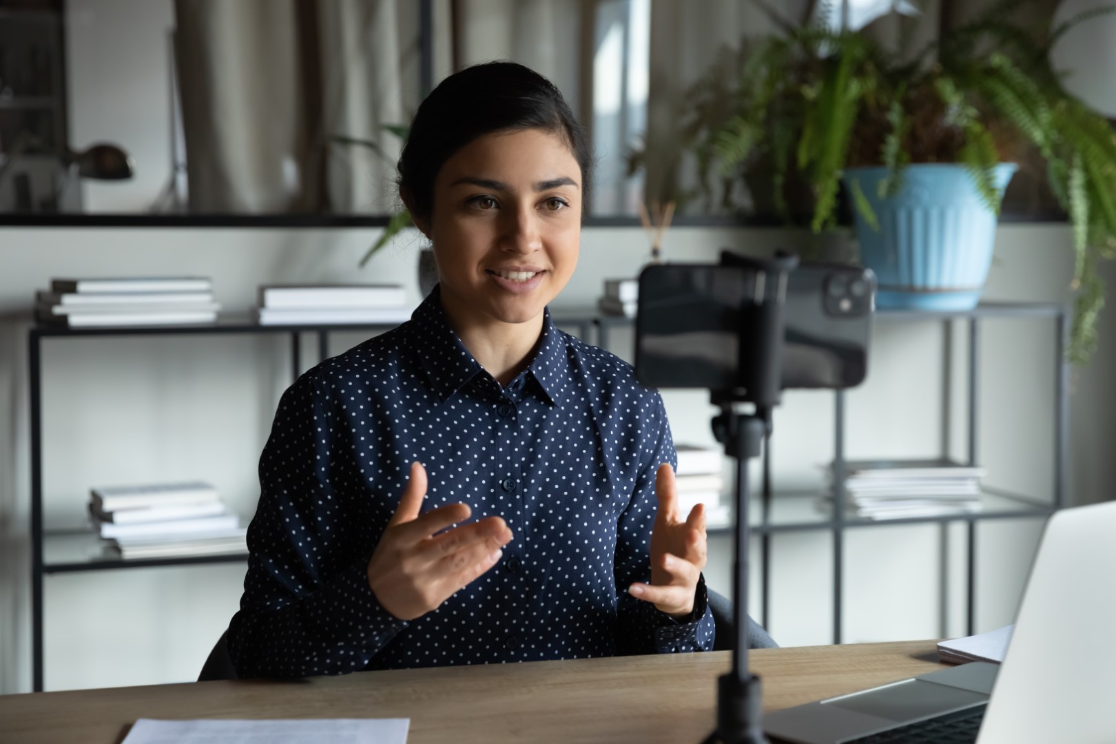 Smiling indian girl sitting in front of smartphone on stabilizer.